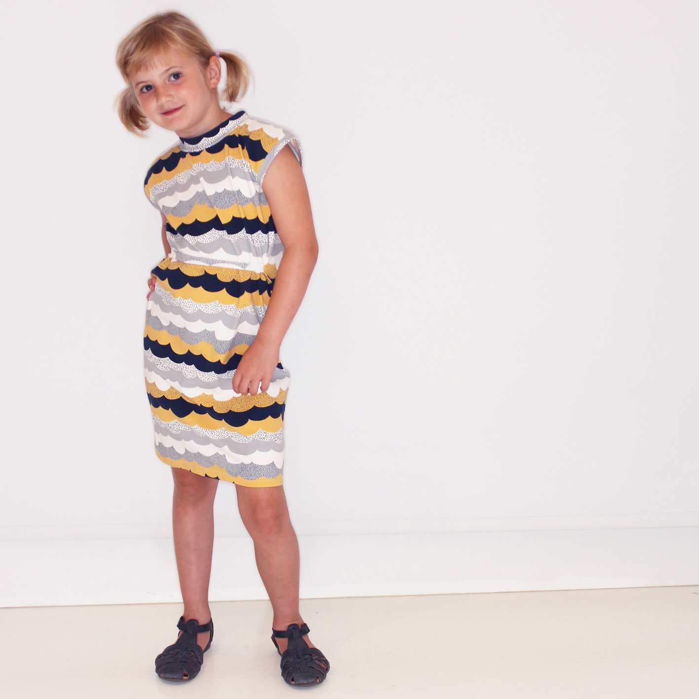Draped cotton dress with yellow clouds print for kids.
