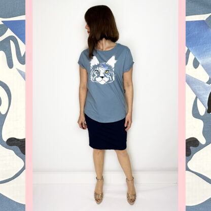 Dusk blue organic cotton Fair Wear shirt featuring a print of Bowie the Cat, with rolled-up sleeves and a rounded hemline, designed by Studio Catta with white, gold, and metallic blue accents.