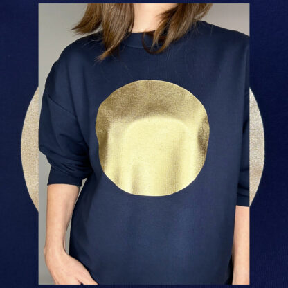 Dark blue oversized organic cotton sweater with golden sun print, sustainable fashion piece from Studio Catta