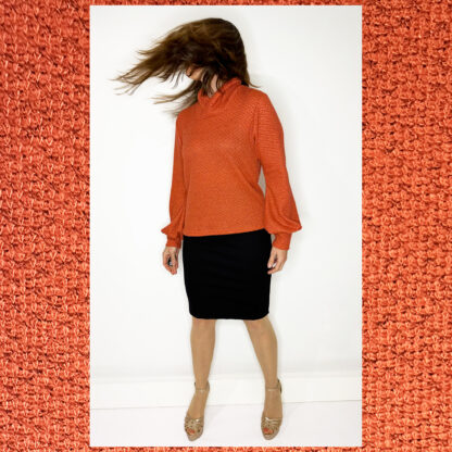 Handmade sustainable sweater by Studio Catta with a crossover turtleneck, puffed sleeves, and a coral and grey mélange design.