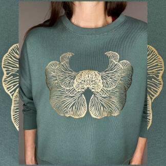 A moss-green sweater with a golden print of the Djamoer Barat mushroom from Sumatra, featuring a roomy and slightly cropped fit. Made of 100% organic cotton, Fairwear-certified, and handprinted in Studio Catta’s boutique atelier in Amsterdam, showcasing sustainable fashion.